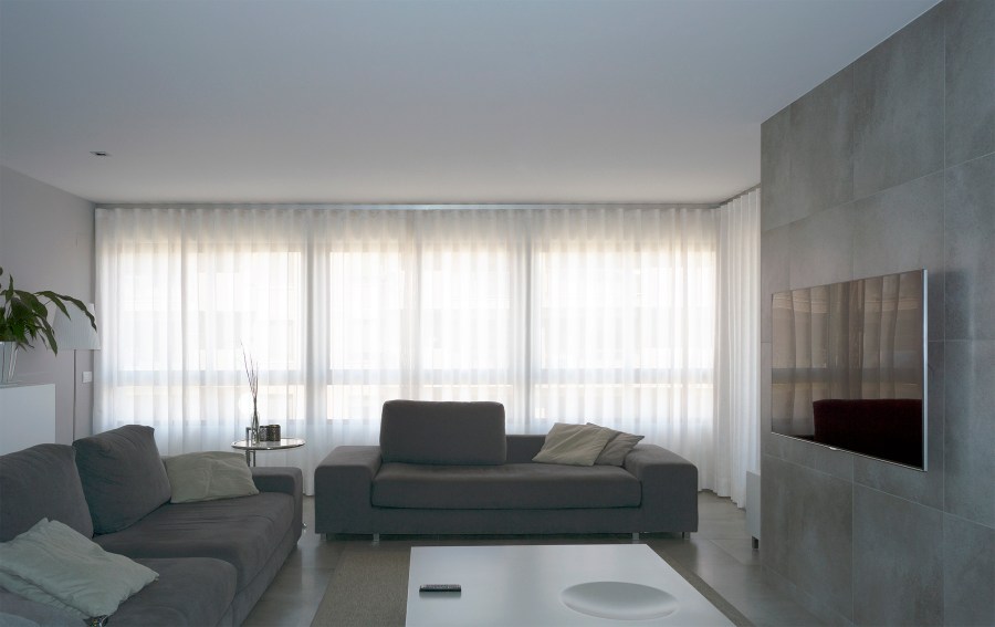Salón moderno balnco y gris con cortinas colocadas en onda perfecta - Villalba Interiorismo